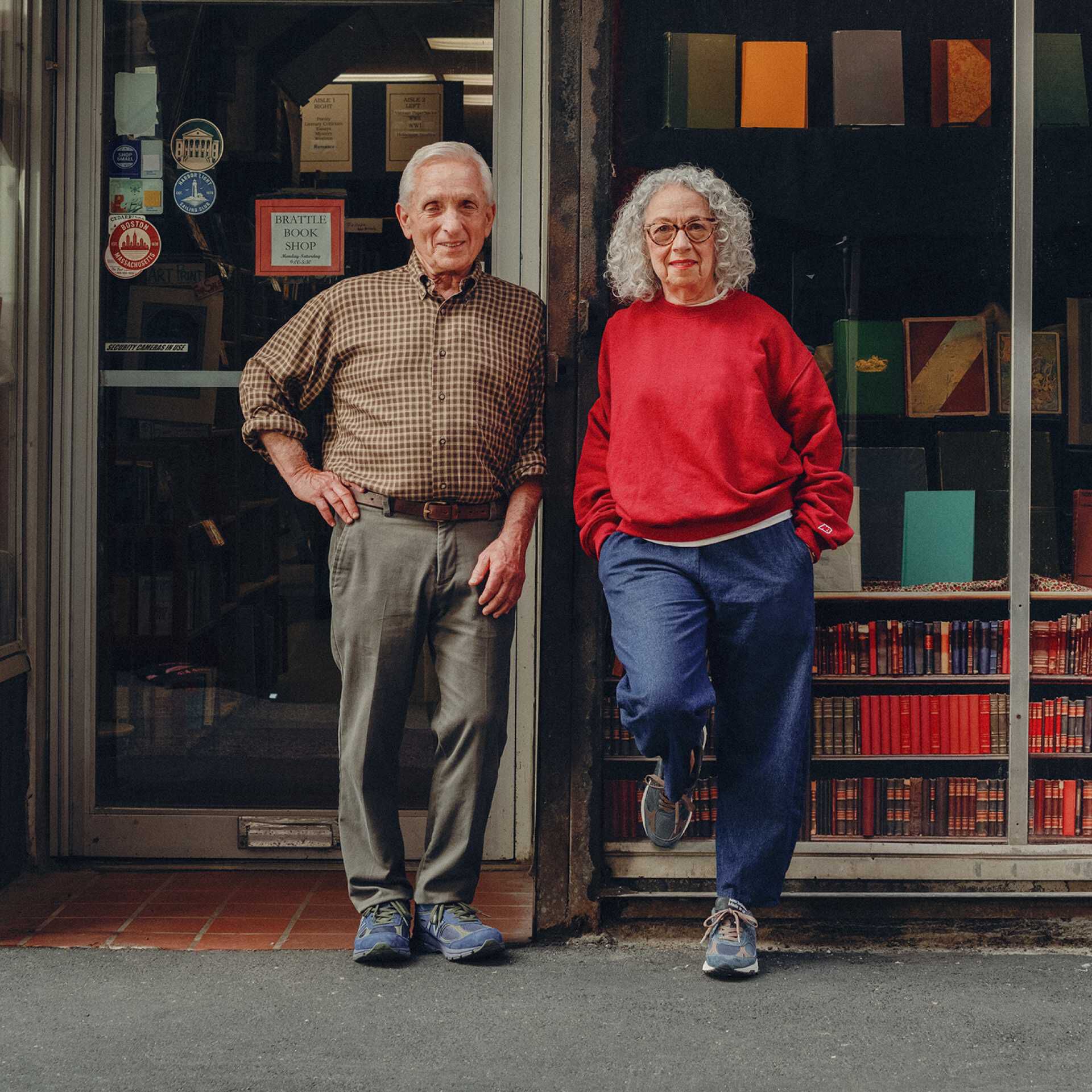 A couple wearing a New Balance standing in front of a store.