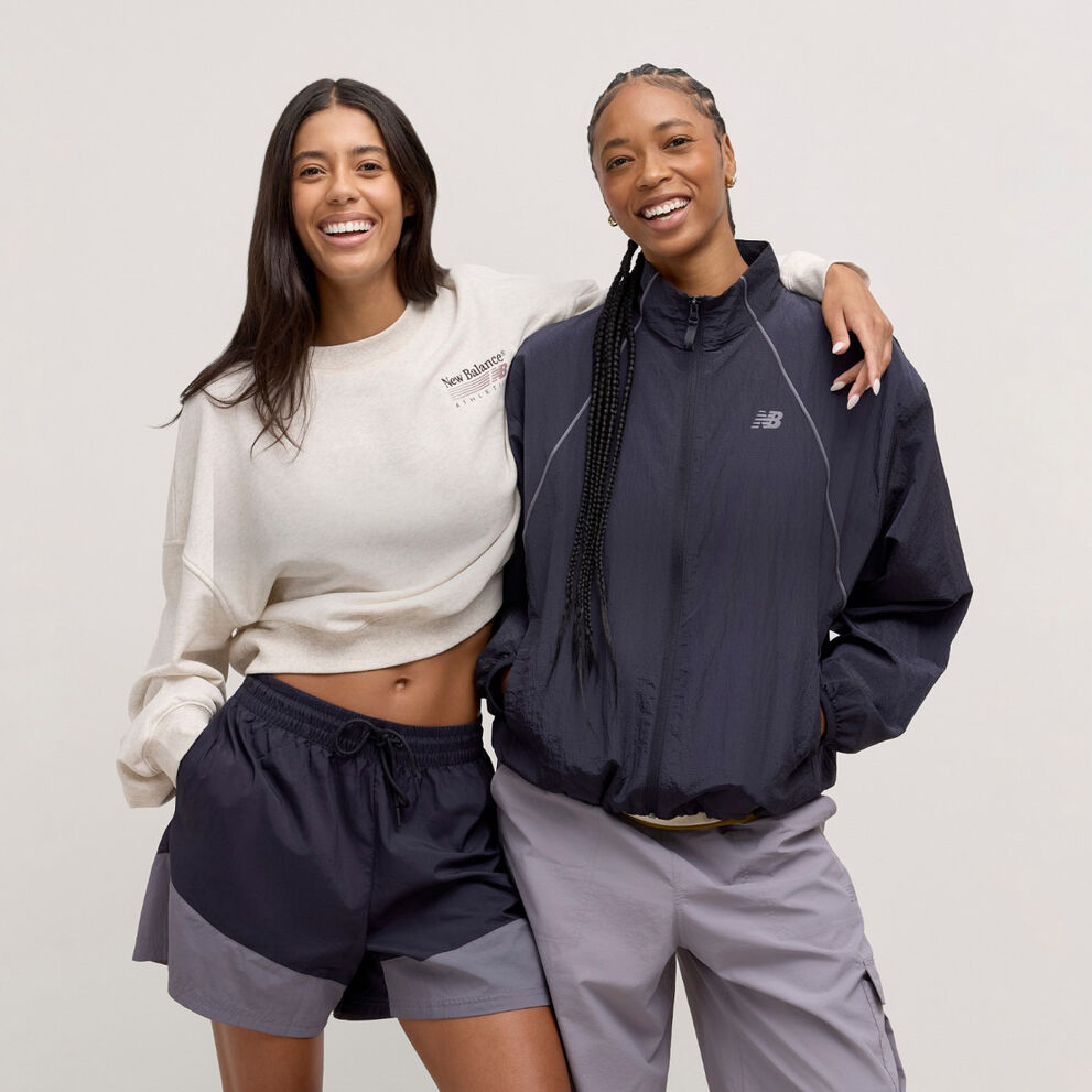Two woman standing back to back and looking at the viewer.