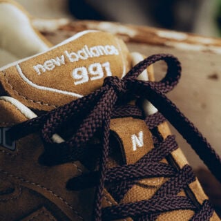 A pair of New Balance Made in UK sneakers sitting in a white studio environment. 