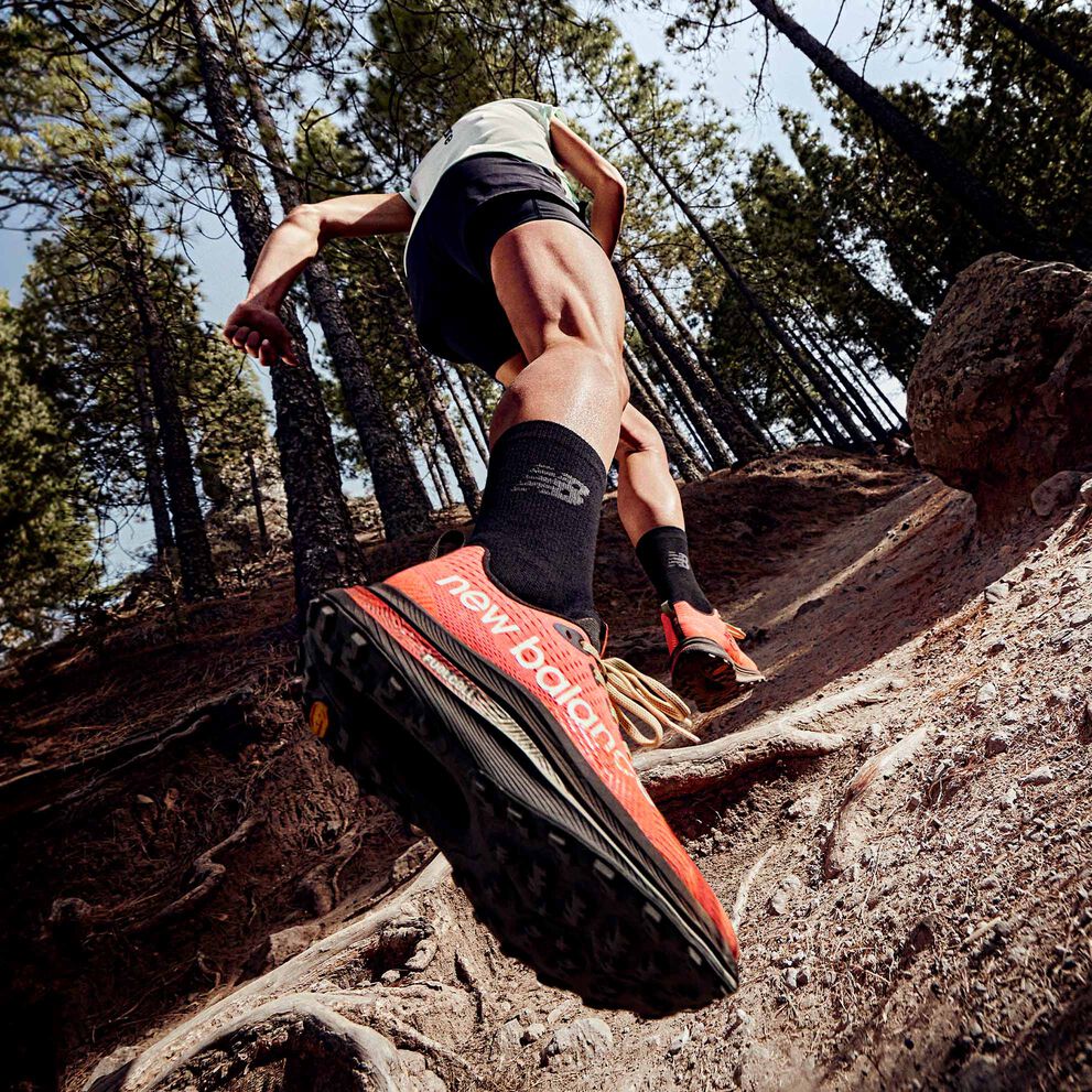 A trail runner running uphill with the New Balance FuelCell SuperComp Trail shoes