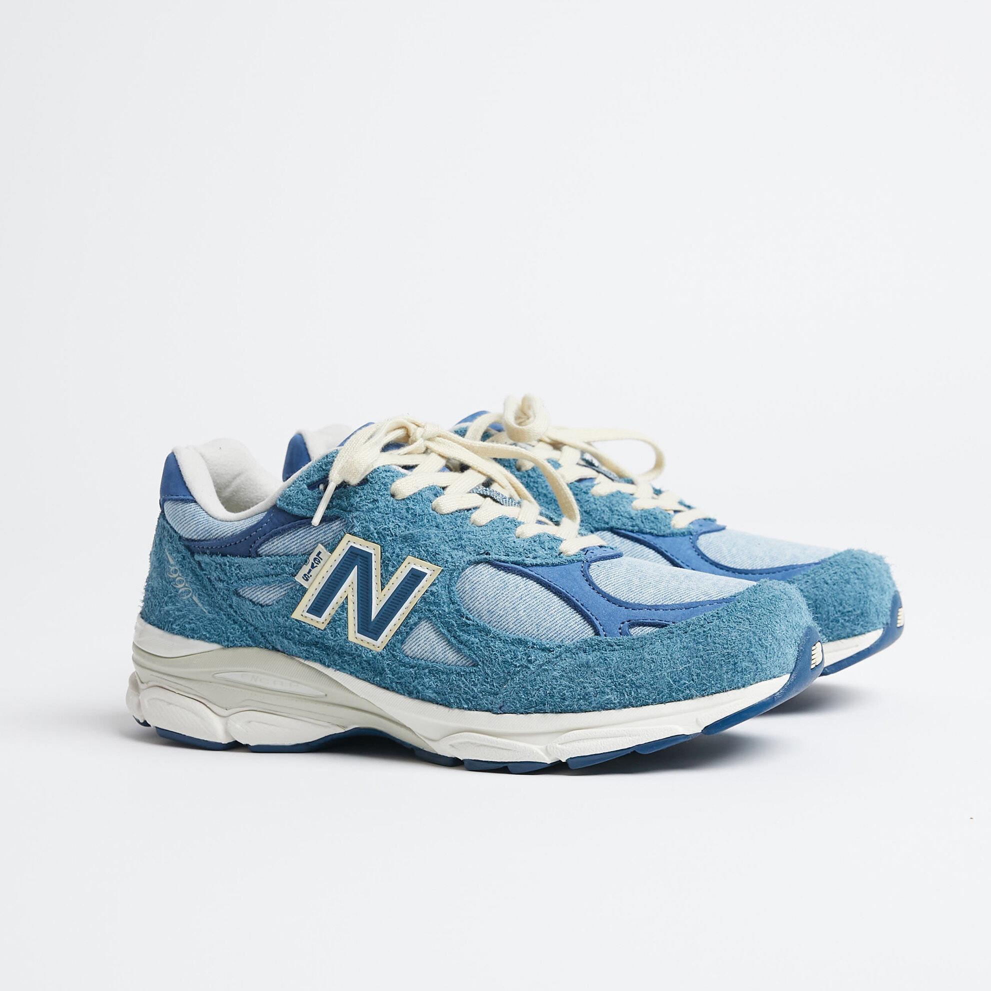 990v3 shoes, one grey and one blue, posed heel to heel in studio enviroment