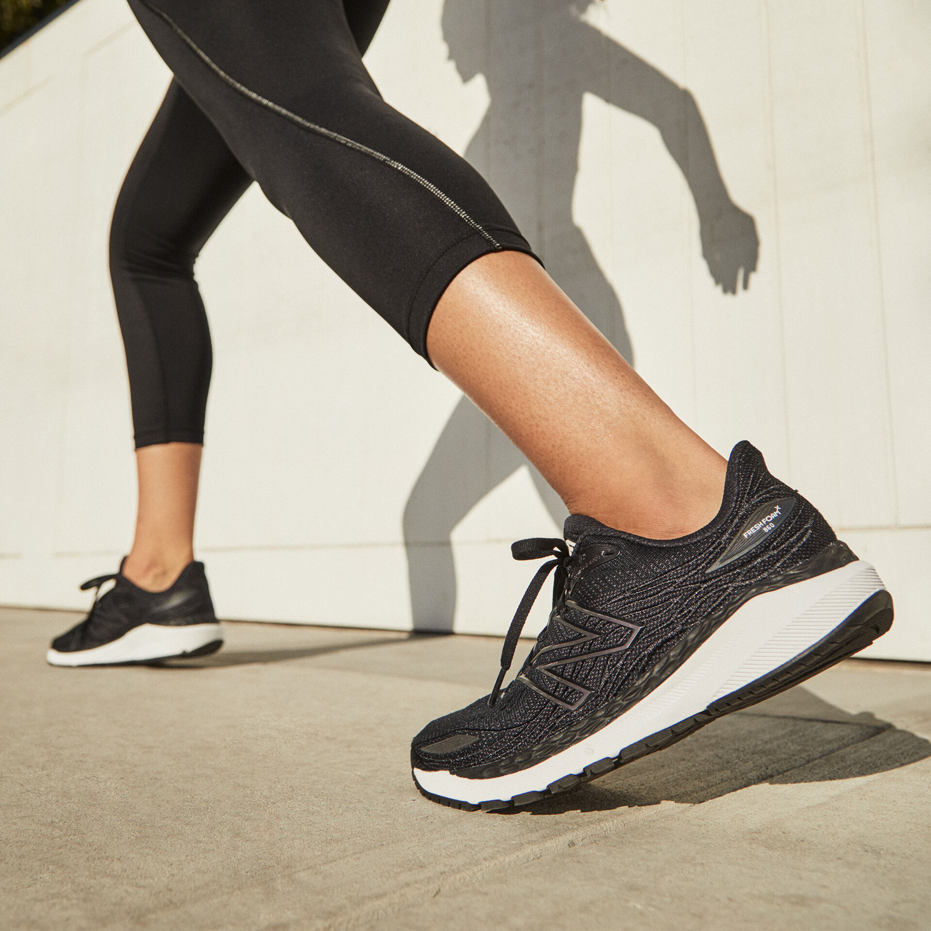 Knee down of a runner wearing black leggings and black Fresh Foam 860v12 shoes, with heels facing slightly forward