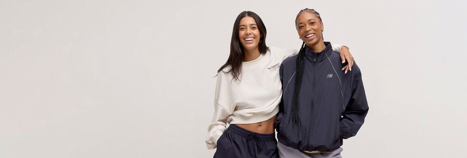 Two woman standing back to back and looking at the viewer.
